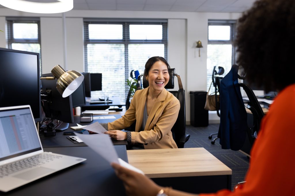 Happy asian businesswoman in office talking with female colleague in office